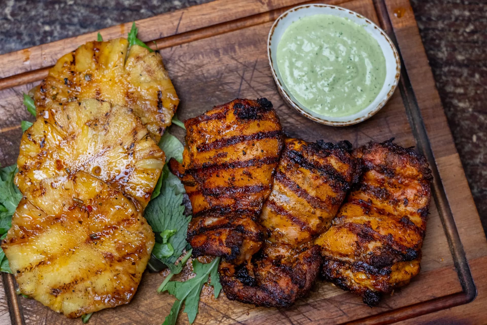 Flame-grilled garlic and spice chicken with grilled pineapple on a wooden board at Saltwood, Ferrymead.