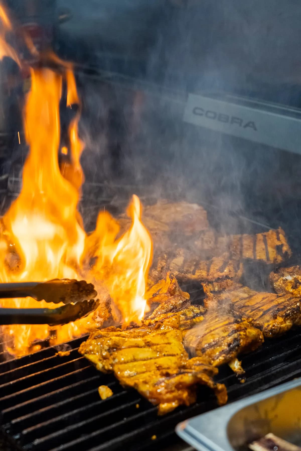 Open wood-fired grill with flames and smoke at Saltwood kitchen, Ferrymead.